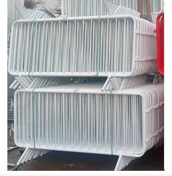 Stack of white fixed leg crowd control barriers in yard