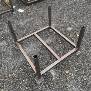 Empty heavy-duty scaffold stillage viewed from above, featuring welded steel square frame, four vertical posts, reinforced base with large square feet for stability on uneven ground.