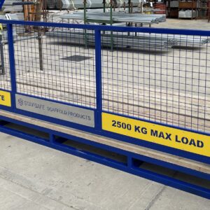 Blue Stay-Safe HDFF-TB heavy-duty loading bay gate front installed on scaffolding, featuring weld mesh panels, toe-board, and 2500 kg max load signage